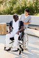 Caregiver walking outdoors with senior man with disability - PhotoDune Item for Sale