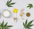 Cosmetic jar, pipette with CBD oil, capsules and tea near green cannabis leaves. Mockup - PhotoDune Item for Sale