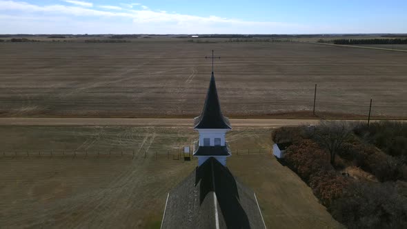 Backwards flying drone revealing secluded old church in Canadian countryside. 4k aerial footage of w