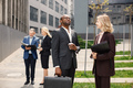 Black businessman standing and talk with caucasian woman in front of modern office - PhotoDune Item for Sale