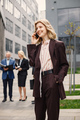 Blonde businesswoman standing and talking on the phone in front of modern office - PhotoDune Item for Sale
