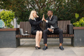 Black businessman sitting on a bench and give a high five to with caucasian woman - PhotoDune Item for Sale