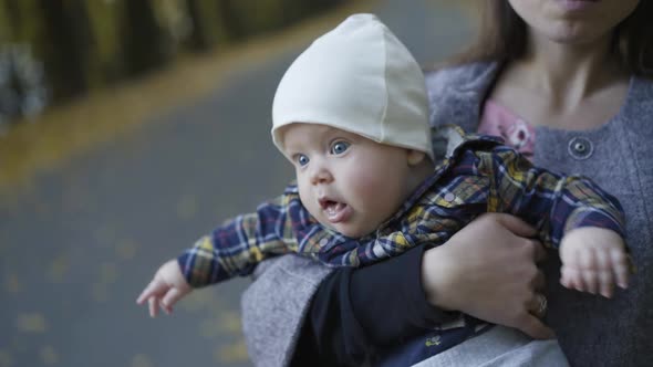 Close View of Young Mother Kisses Her Baby Boy When Holds Him on Hands