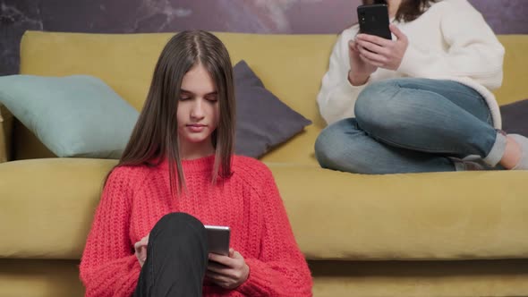 Girl is Watching a Movie While Her Mother Reading the News Using a Phone