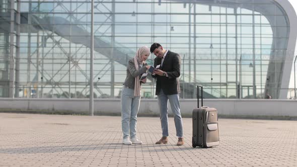 Muslim Lady in Hijab and Arab Man are Glad and Jumping Together Standing Outside Modern Airport