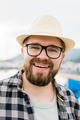 Close-up handsome millennial man wearing hat and glasses near marina with yachts. Portrait of - PhotoDune Item for Sale