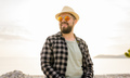 Handsome and confident. Outdoor portrait of smiling millennial man wearing hat and sunglasses on - PhotoDune Item for Sale