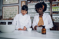 Multiracial pharmacists are standing in a vintage apothecary and making a drug. - PhotoDune Item for Sale