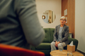 A senior woman is sitting on a couch in a doctor's office and talking with a psychotherapist - PhotoDune Item for Sale