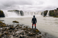 Back view of a man standing next to the river with waterfalls and watching a majestic view. - PhotoDune Item for Sale