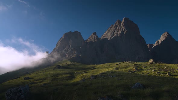 Wide Dynamic Range Panorama of a Rocky Mountain with Clouds Surrounded By Green Grass in the Evening