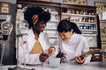 Multicultural pharmacists are making a traditional cure in a vintage pharmacy. - PhotoDune Item for Sale