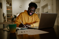 A happy african american remote worker is sitting at home late at night - PhotoDune Item for Sale