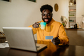 Interracial man is sitting at home and spending money online. - PhotoDune Item for Sale