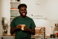 An interracial man is standing in his cozy apartment and enjoying coffee or tea. - PhotoDune Item for Sale