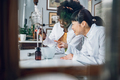 Interracial chemists are using lab vessels and making a drug in a vintage apothecary. - PhotoDune Item for Sale