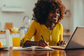 A cheerful african american female freelancer is writing down notes and tasks - PhotoDune Item for Sale