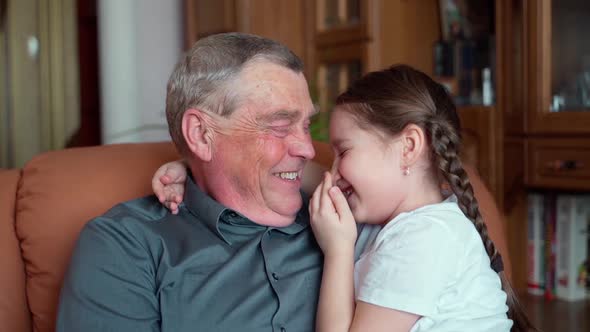 Slow motion video. Loving beautiful young little girl granddaughter hug her elderly 60s grandfather