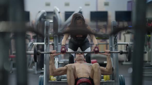 Front View Female Personal Trainer Helping Securing Male Sportsman Lifting Barbell