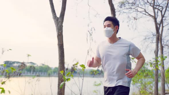 Asian young active sport male wear mask run on street in public park.