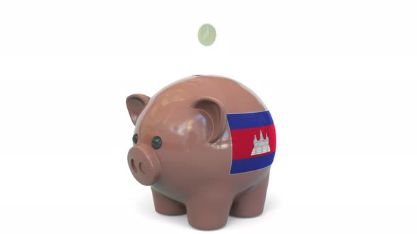 Putting Money Into Piggy Bank with Flag of Cambodia
