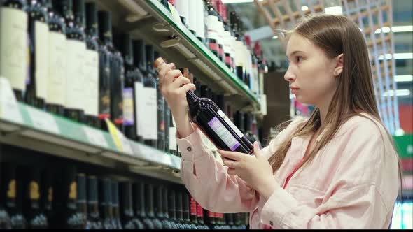 Young Woman is Buying Red Wine in Alcohol Shop