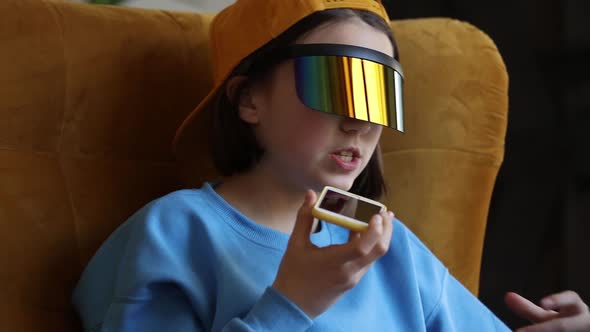 Stylish girl in yellow hat and blue sweater using mobile phone and laptop computer at home