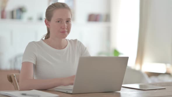 Beautiful Young Woman Pointing Towards Camera While Using Laptop in Office