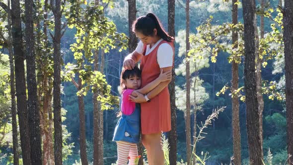 Young mother comforts her upset little daughter at a camp in the woods. with love and care.