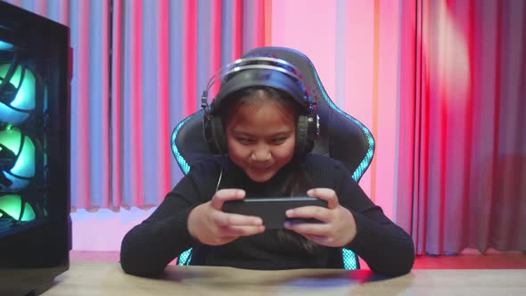 Happy Girl Focused On Playing Video Games On Her Smartphone alt