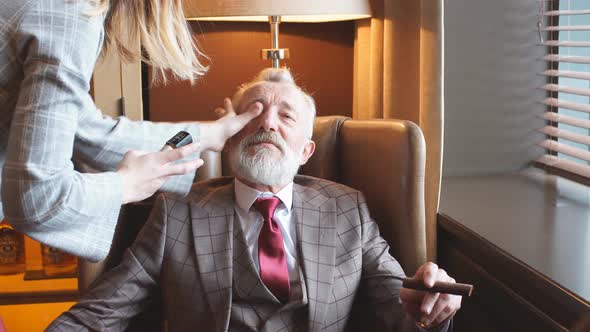 Makeup Artist Corrects Makeup on the Face of an Elderly Actor.