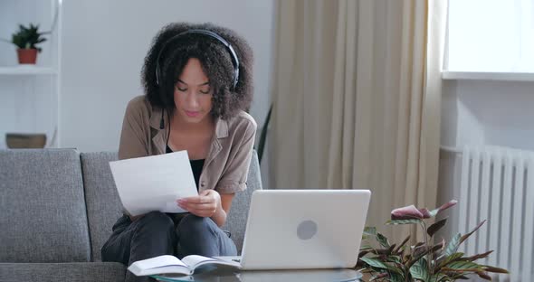 Young African Woman Entrepreneur Wear Headset Making Conference Business Call Working Home Sitting