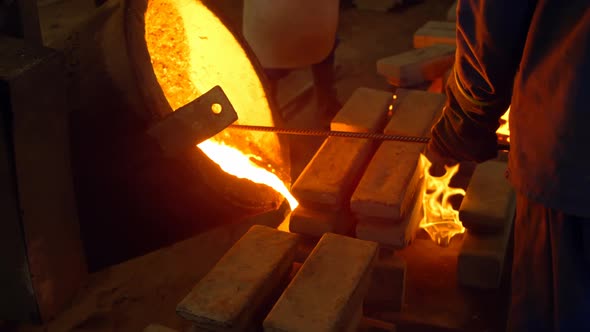 Male worker pouring molten metal in mold at workshop 4k