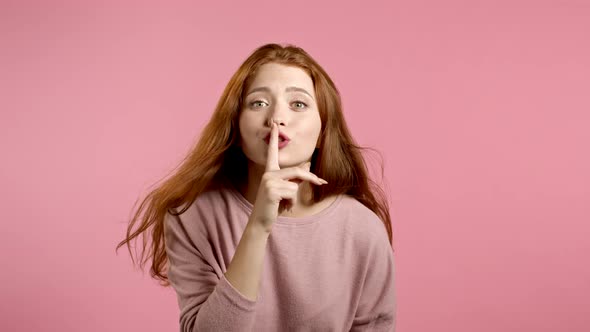Beautiful Woman Holding Finger on Her Lips Over Pink Background. Gesture of Shhh, Secret, Silence