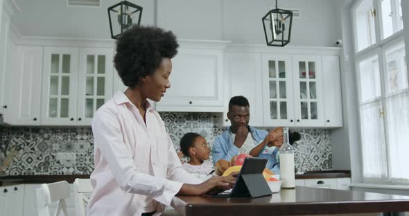 African American Mother Working on Tablet Computer at the Kitchen Table