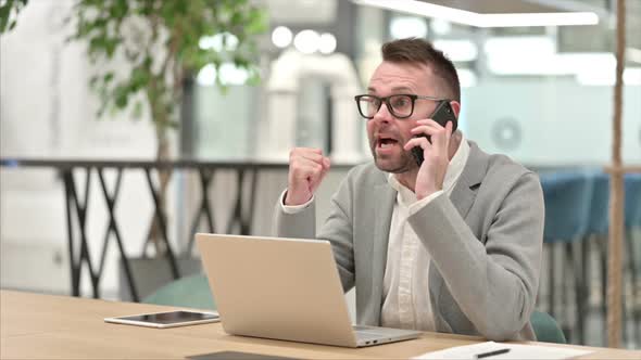 Angry Creative Man Arguing on Phone Call at Work