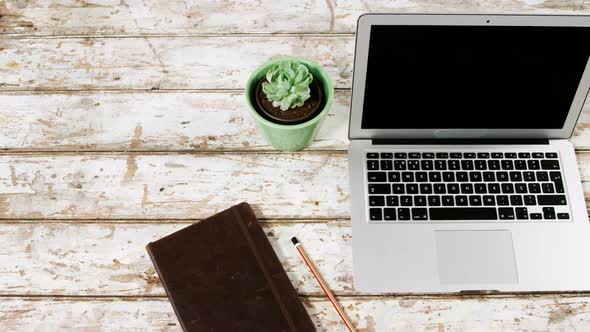 Laptop, pot plant, diary and mobile phone