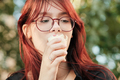 Beautiful red-haired teenage girl with glasses eats ice cream in a waffle cup. - PhotoDune Item for Sale