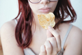 Red-haired girl holds one potato chip in her hand near her mouth, close-up. - PhotoDune Item for Sale