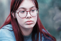 Portrait of a sad girl with glasses. Pensive red-haired teenage girl in a blue T-shirt. - PhotoDune Item for Sale