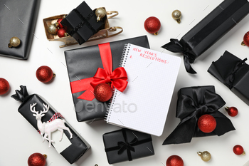 Notepad with list and gift boxes on white background, top view