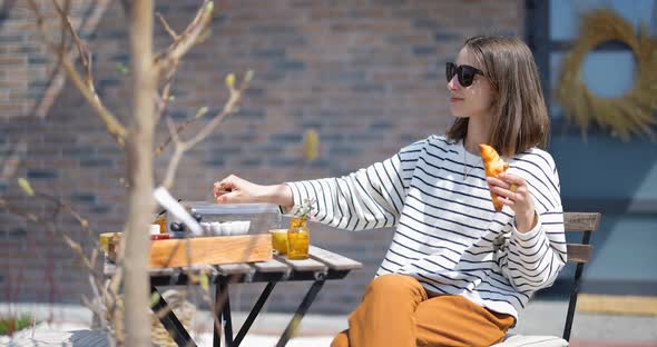 Woman Having a Breakfast with Croissants and Coffee Outdoors