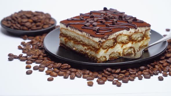 Portion of Traditional Italian Tiramisu dessert and coffee beans on white background