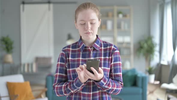 Young Woman Standing And Using Smart Phone