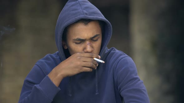 African Teenager Coughing Trying to Smoke Outdoors, Inhaling Harmful Nicotine