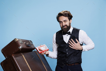  treatment, posing in studio with box of cardiovascular medicaments. Man doorkeeper having drugs package in hand, next to luggage.
