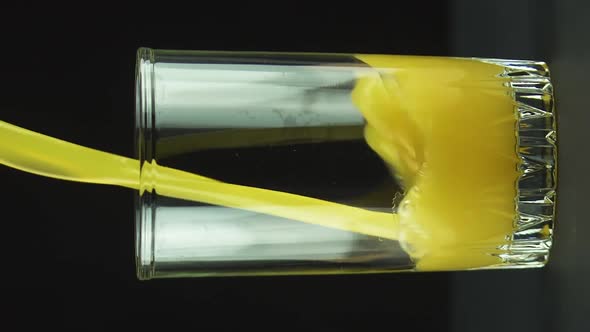 Vertical Video Juice Pouring Into Glass Isolated on Black Background