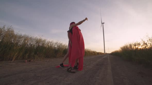 Two Stylish Girls in Red Cloth Take a Selfie on the Background of Wind Generators in the Field