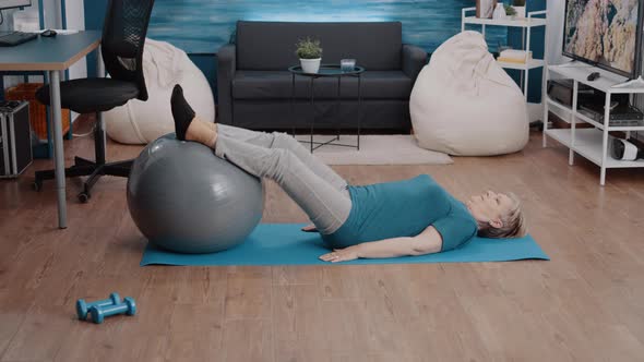 Woman Using Fitness Toning Ball to Train Leg Muscles on Mat