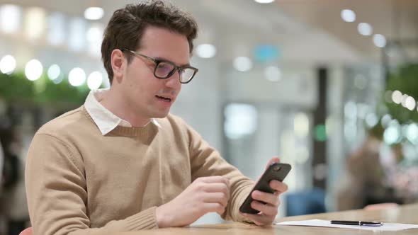 Excited Man Celebrating on Smartphone in Office